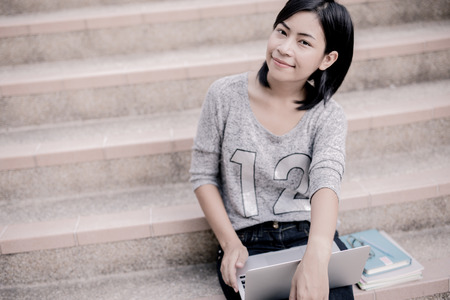 attractive female college student sitting on stairsの写真素材