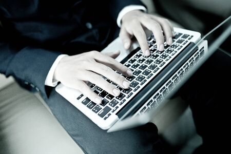 Young business using laptop in back seat of carの写真素材