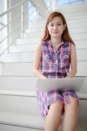 Young professional business woman sitting on the steps of an old stone building using a laptop computer working outdoorsの写真素材