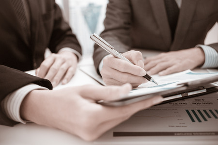 Two businessmen looking at report and having a discussion in office.の写真素材