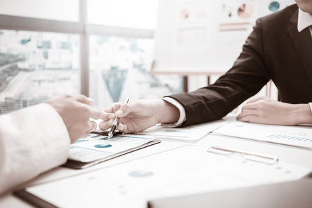 Two businessmen looking at report and having a discussion in office.の写真素材