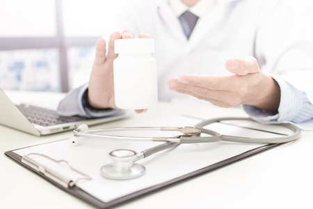 doctor showing a bottle of pills to the patientの写真素材