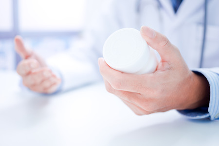 doctor showing a bottle of pills to the patientの写真素材