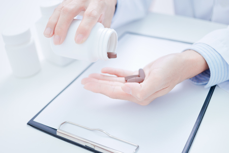 doctor showing a bottle of pills to the patientの写真素材