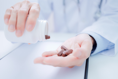 doctor showing a bottle of pills to the patientの写真素材