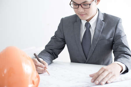 Closeup cropped image of a young male architect working on blueprints spread out on a tableの写真素材