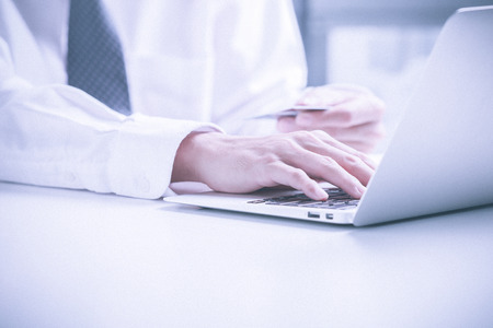 Man holding credit card in hand and entering security code using laptop keyboardの写真素材