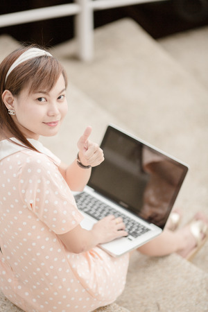 Young woman using laptop on steps outdoorsの写真素材