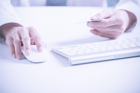 Man holding credit card in hand and entering security code using laptop keyboardの写真素材