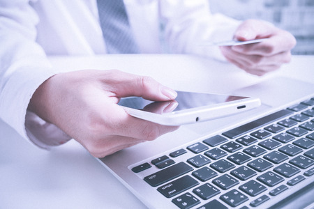 Man holding credit card in hand and entering security code using laptop keyboard