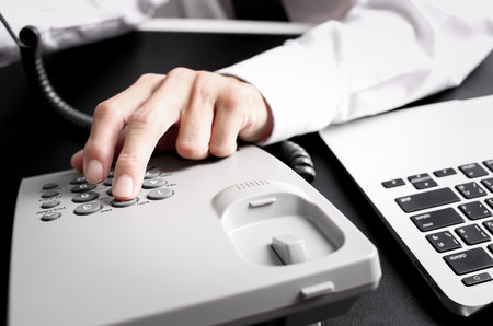 loseup of dialing a telephone number on a black landline telephone