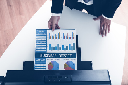 Businessman analyzing investment charts with printer. Accounting