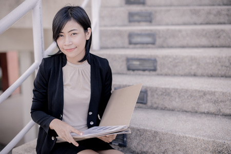 Young businesswoman sitting on stairs of building,の写真素材