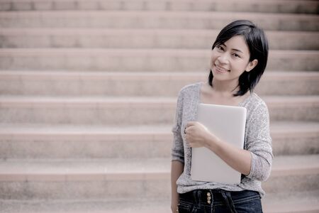 attractive female college student sitting on stairsの写真素材