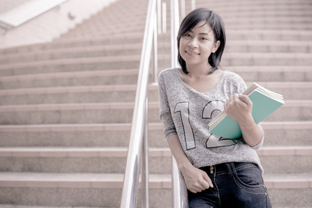 attractive female college student sitting on stairsの写真素材