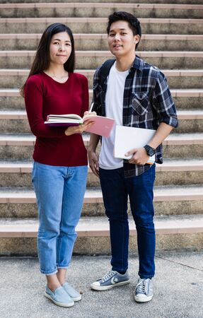 Two students studying with computer notebook outdoors
