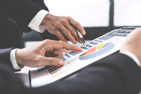 Two businessmen looking at report and having a discussion in office.