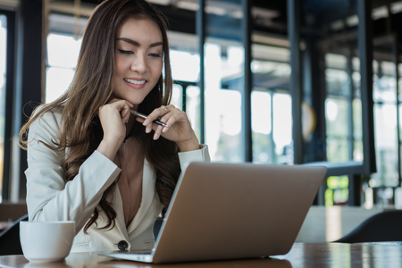 Businesswoman drinking coffee / tea and using tablet computer in a coffee shopの写真素材