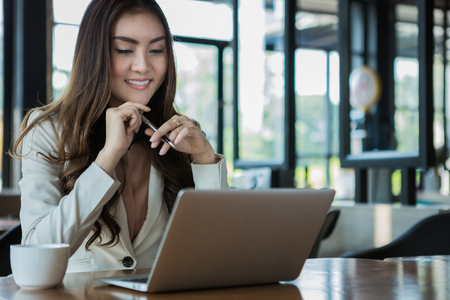 Businesswoman drinking coffee / tea and using tablet computer in a coffee shopの写真素材