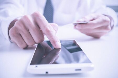 Closeup of man's hands holding credit cards and using mobile phone. Concept for m-commerce, online shopping, m-banking, internet security.の写真素材
