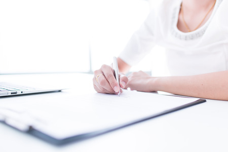 Hands of young businesswoman signing paper