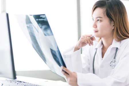 Woman Doctor Looking at X-Ray Radiography in patient's Roomの写真素材