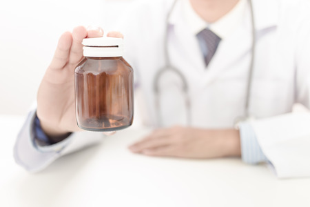 doctor showing a bottle of pills to the patientの写真素材