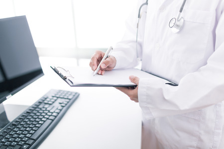 Close-up view of female doctor hands filling patient registration form. Healthcare and medical conceptの写真素材