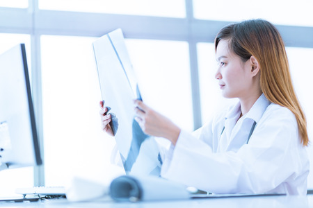 Woman Doctor Looking at X-Ray Radiography in patient's Roomの写真素材