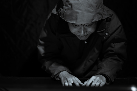 Hooded computer hacker stealing information with laptop