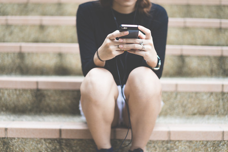 Woman students sitting on stairs with their smartphonesの写真素材