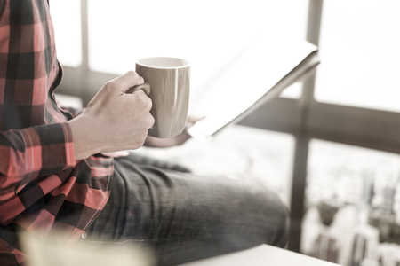 Young man having cup of coffee reading newspaperの写真素材