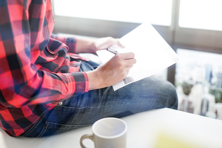 Young man having cup of coffee reading newspaperの写真素材