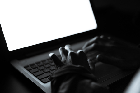 Hooded computer hacker stealing information with laptopの写真素材