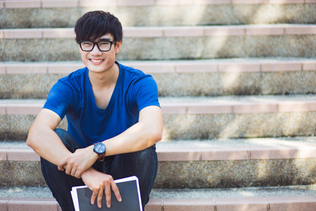 Smiling college student sitting on staircaseの写真素材