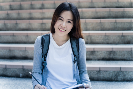 Smiling college student sitting on staircaseの写真素材