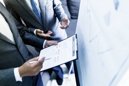 Image of two young businessmen discussing project at meeting
