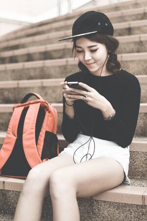 Woman students sitting on stairs with their smartphones