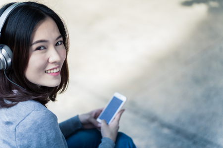 Woman students sitting on stairs with their smartphonesの写真素材