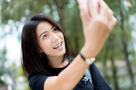 Beautiful young woman photographing herself with phone.の写真素材