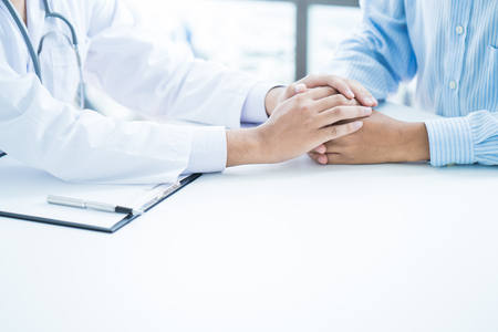 male doctor comforting patient at consulting roomの写真素材