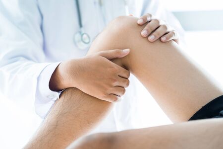 Close-up of male physiotherapist massaging the leg of patient in a physio room.の写真素材