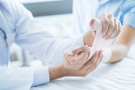 Close-up doctor is bandaging upper limb of patient.の写真素材