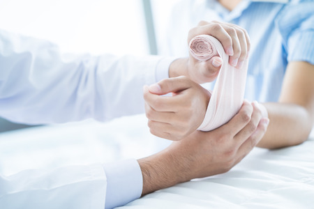 Close-up doctor is bandaging upper limb of patient.の写真素材