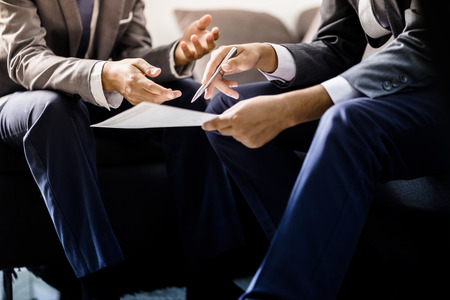 Image of two young businessmen discussing project at meeting