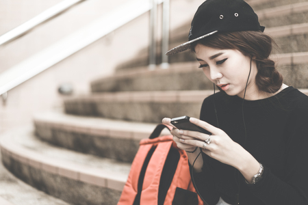 Woman students sitting on stairs with their smartphonesの写真素材