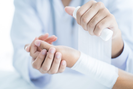 Close-up doctor is bandaging upper limb of patient.の写真素材
