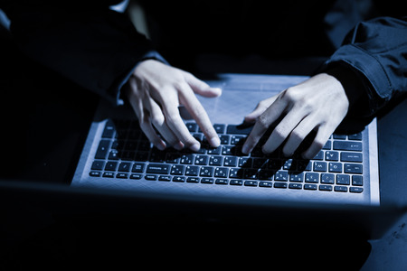 Hooded computer hacker stealing information with laptopの写真素材