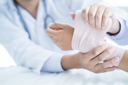 Close-up doctor is bandaging upper limb of patient.の写真素材