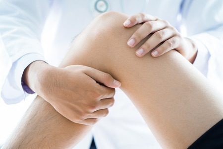 Close-up of male physiotherapist massaging the leg of patient in a physio room.の写真素材